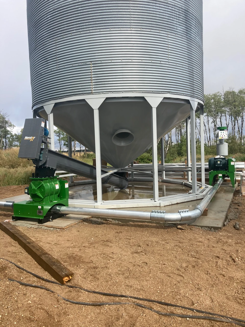 Green blower units and pipe connections beneath a hopper bin