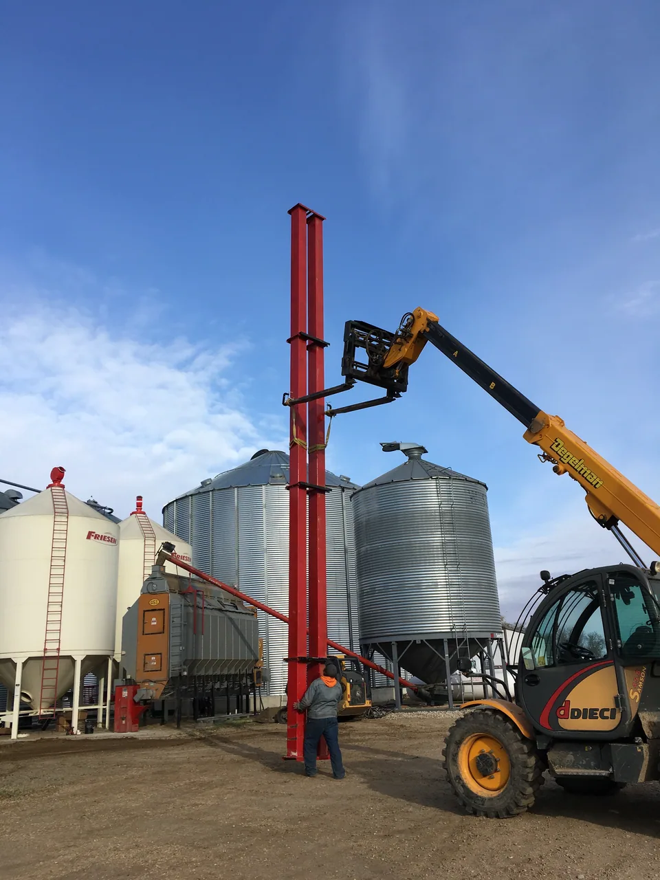 Positioning the red bucket elevator beside the dryer