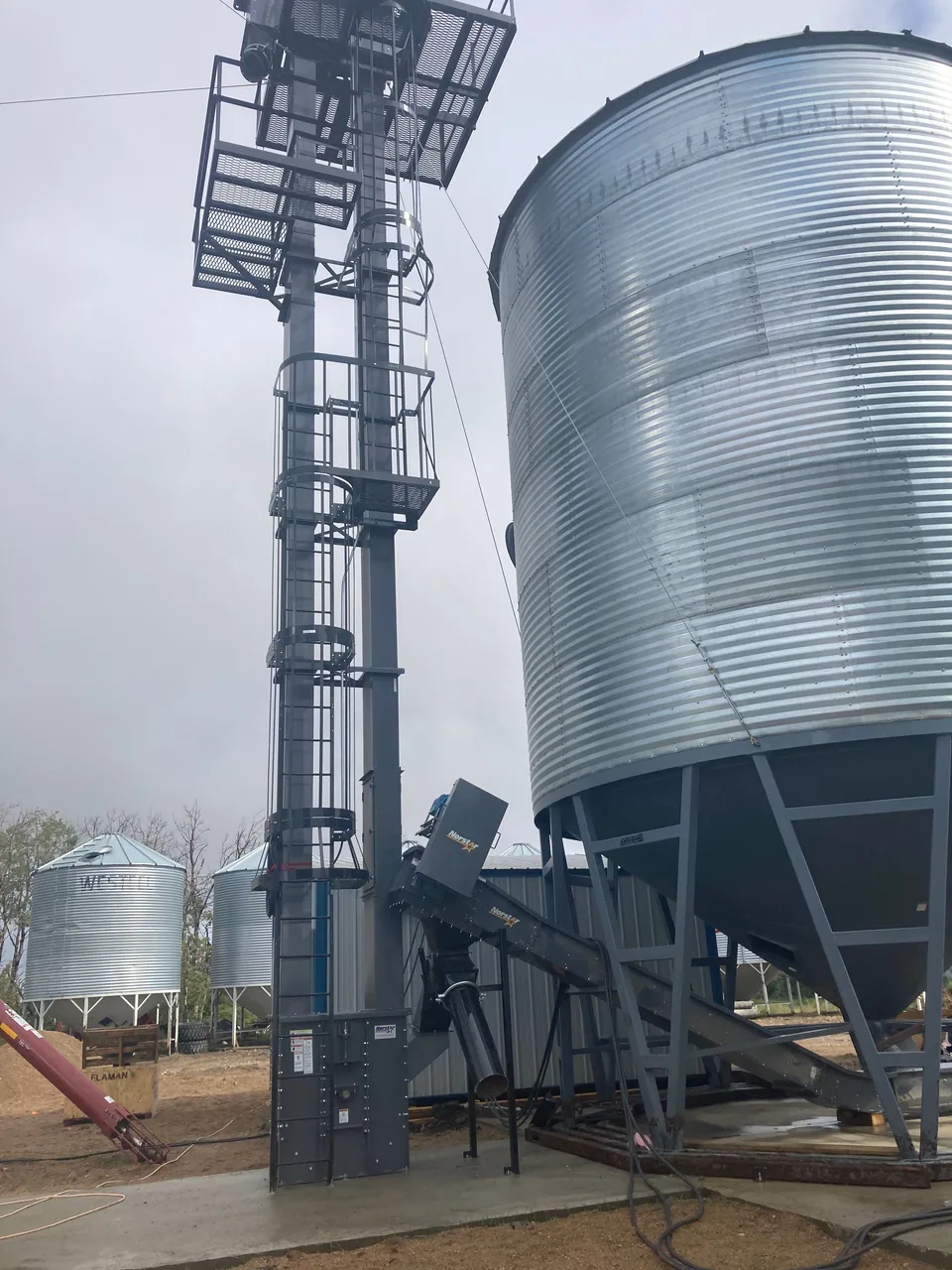 Bucket elevator and inlet connection beside a hopper bin