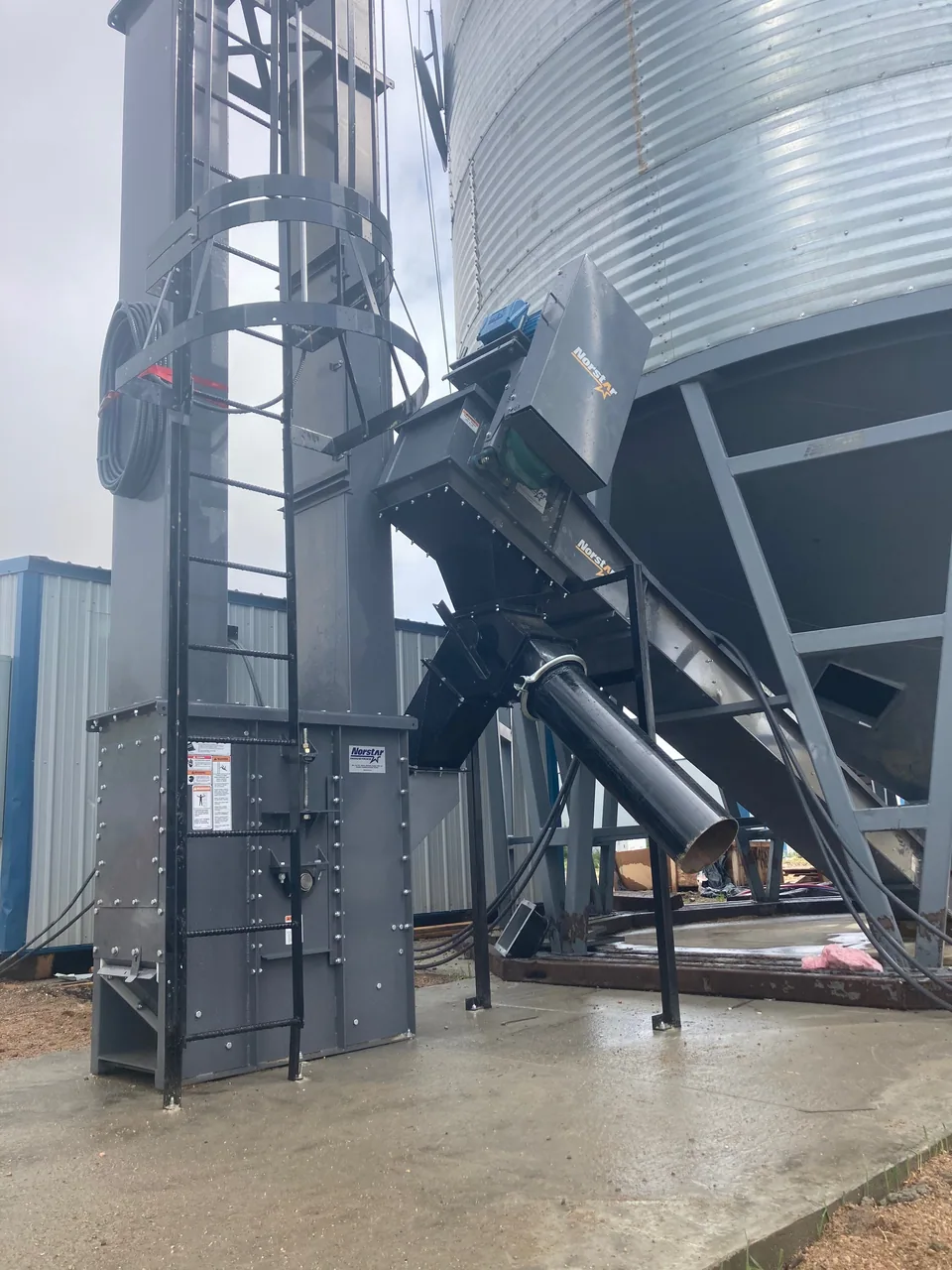 Bucket elevator and inlet connection beside a hopper bin